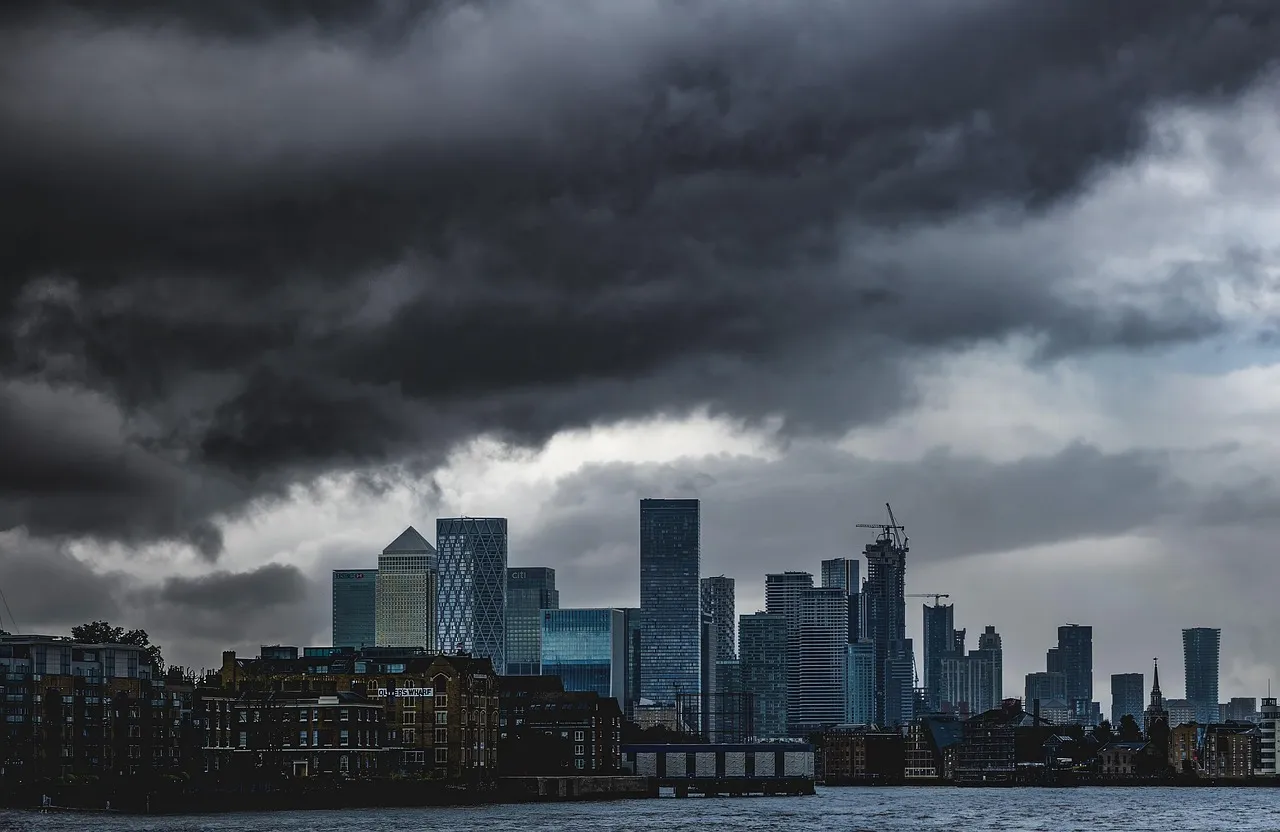 The skyscrapers of Canary Wharf across the River Thames under dark storm clouds