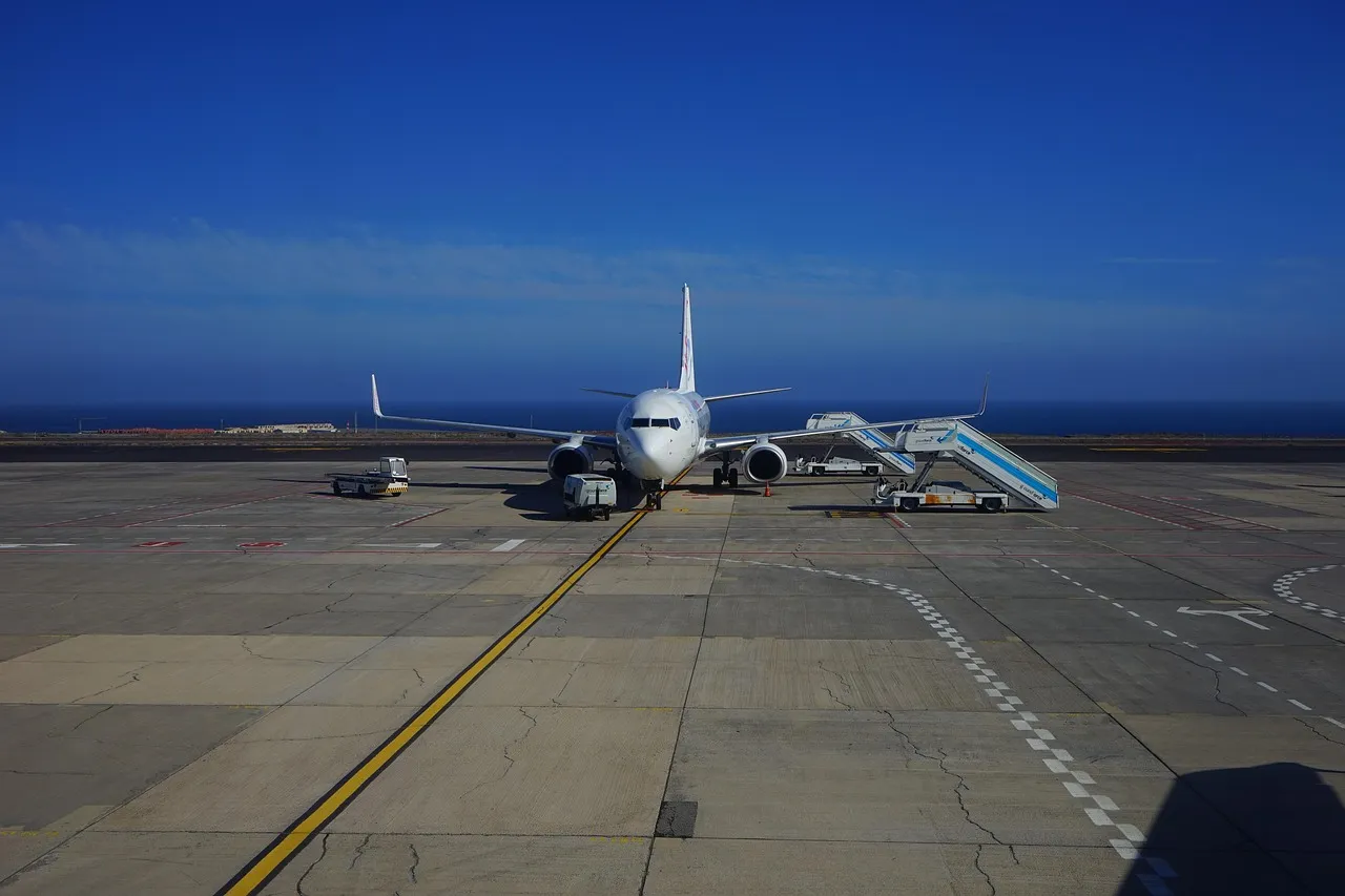 A passenger jet parked on an airport apron with boarding stairs beside it, under a clear blue sky