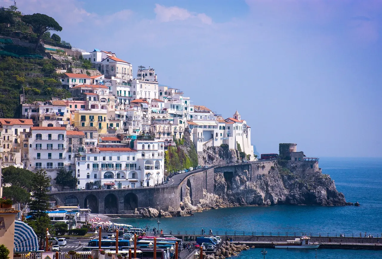 Pastel houses of Amalfi stacked up the steep green hillside above the harbour and a calm blue sea