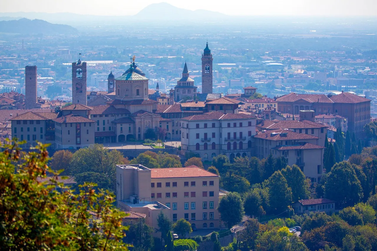 The domes and towers of Bergamo's walled upper town above the trees