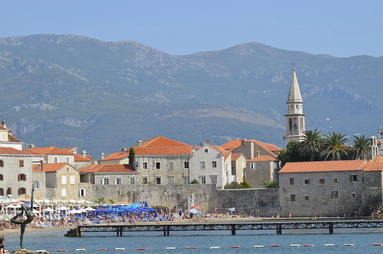 Budva's walled old town and bell tower by the sea, with mountains behind