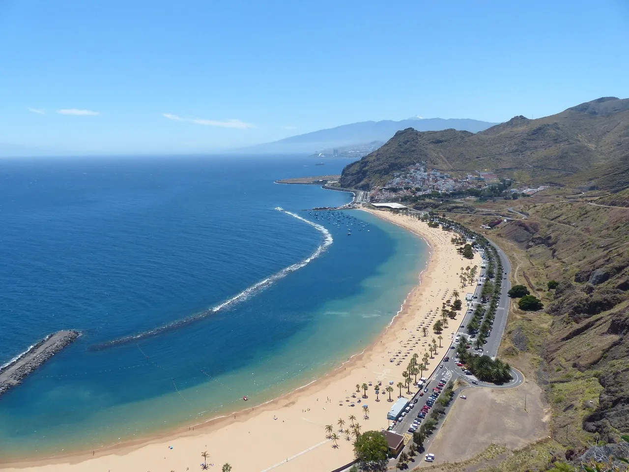 The long golden beach of Las Teresitas near Santa Cruz de Tenerife, with a calm breakwater lagoon and dry hills behind
