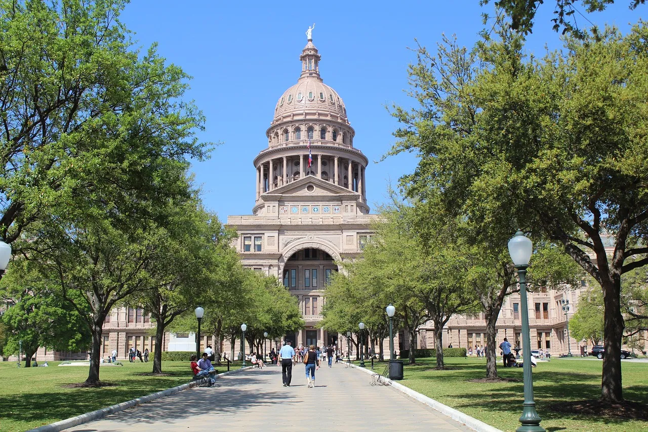 A tree-lined path leading to the domed Texas State Capitol