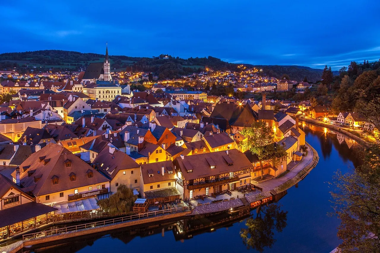 Český Krumlov lit up at dusk inside a loop of the Vltava river