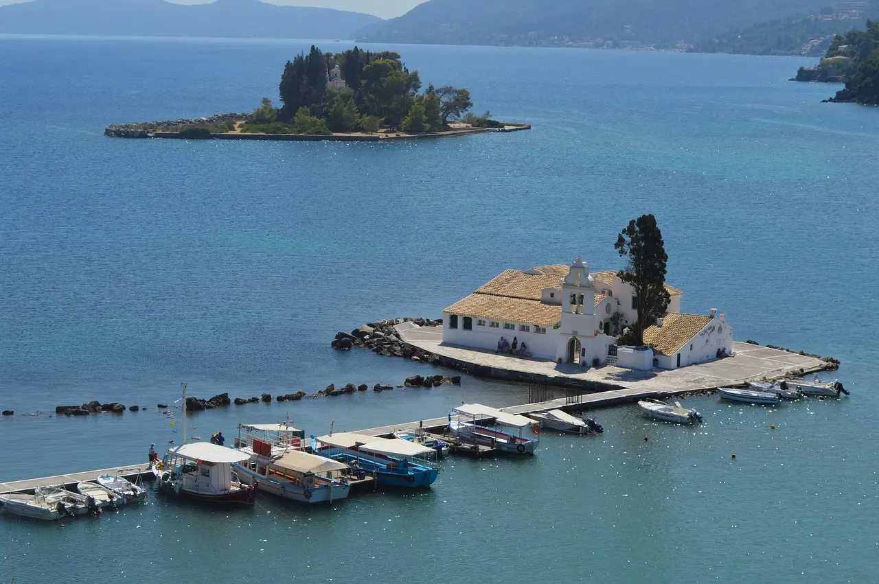 Vlacherna Monastery on its little islet joined by a causeway, with Mouse Island behind it in the calm sea off Corfu