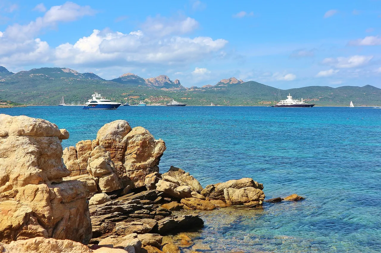 Granite rocks and clear turquoise sea on Sardinia's Costa Smeralda, with yachts in the bay