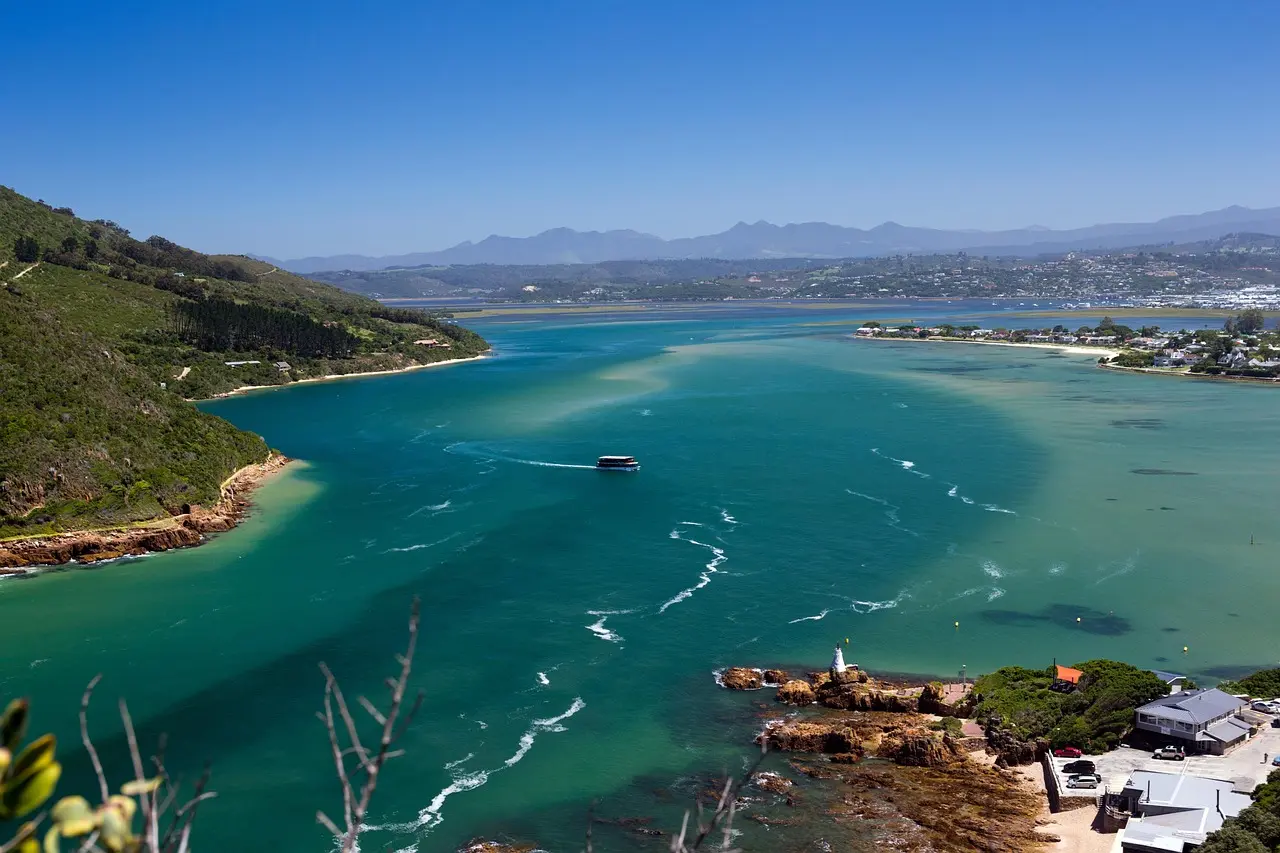 The turquoise Knysna lagoon opening to the sea between green headlands, with the town and mountains beyond
