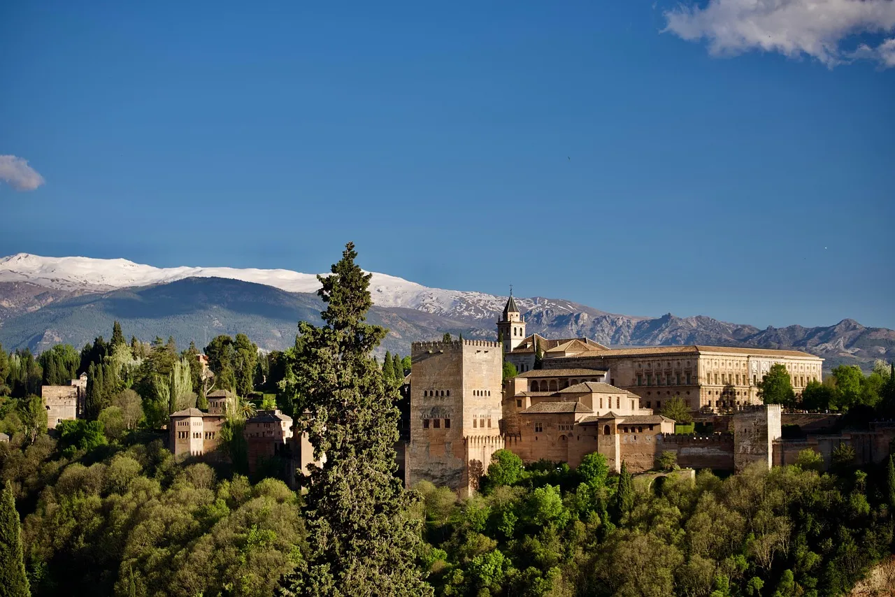 The Alhambra palace on its wooded hill in Granada, with the snowy Sierra Nevada behind