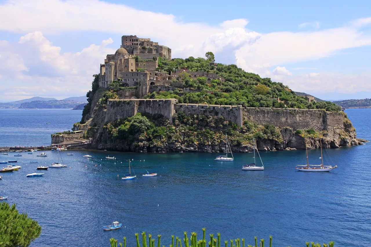 The Aragonese Castle on its rocky islet off Ischia, joined to the island by a causeway, with sailing boats in the blue bay
