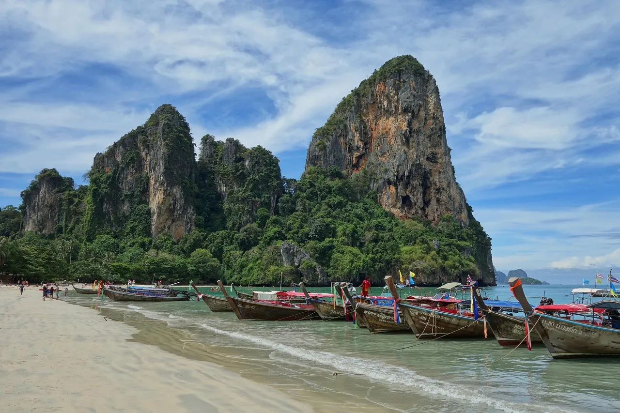 Long-tail boats on the beach below limestone cliffs at Railay in Krabi