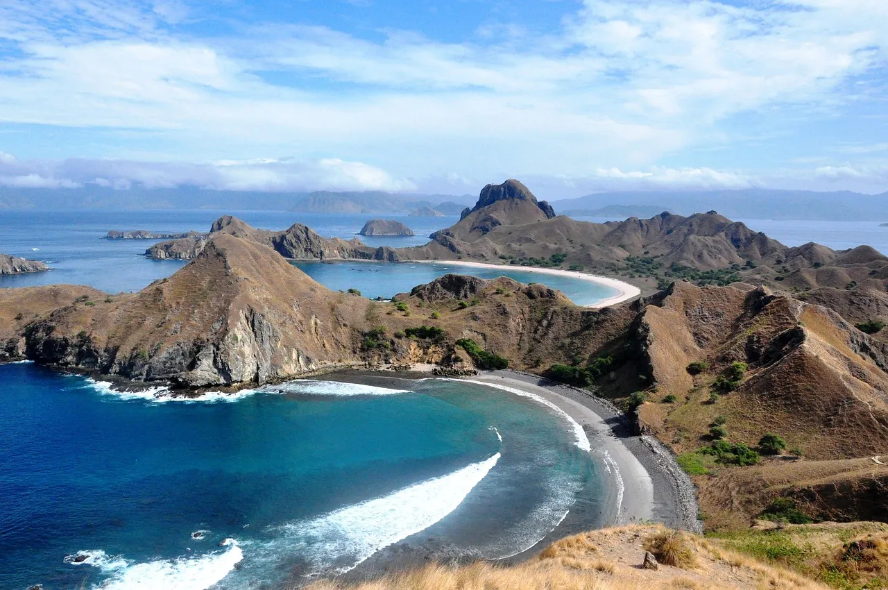 The view from the top of Padar Island in Komodo National Park, with curved bays and beaches between brown hills and blue sea
