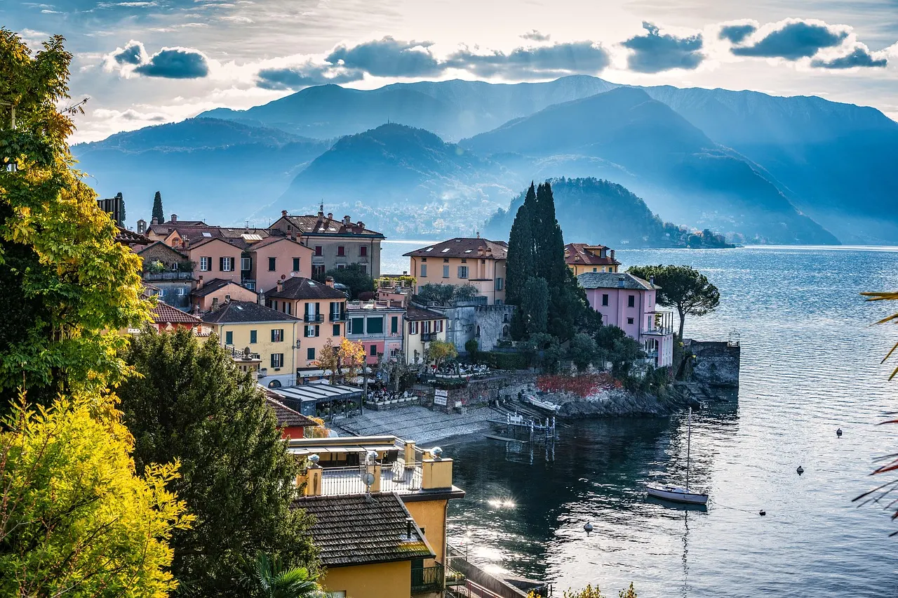 Colourful lakeside houses and a church tower at the water's edge on Lake Como, with mountains behind