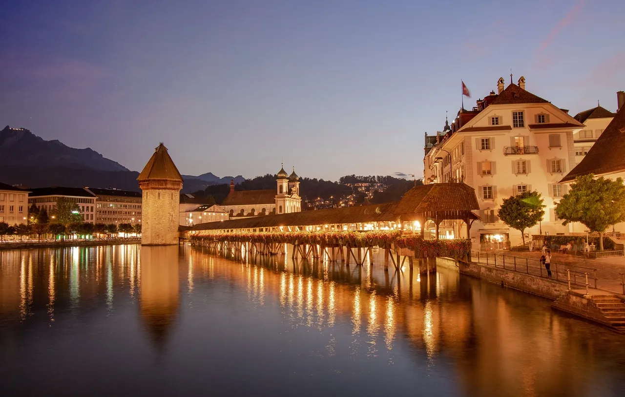 The Chapel Bridge and its water tower in Lucerne, lit up at dusk
