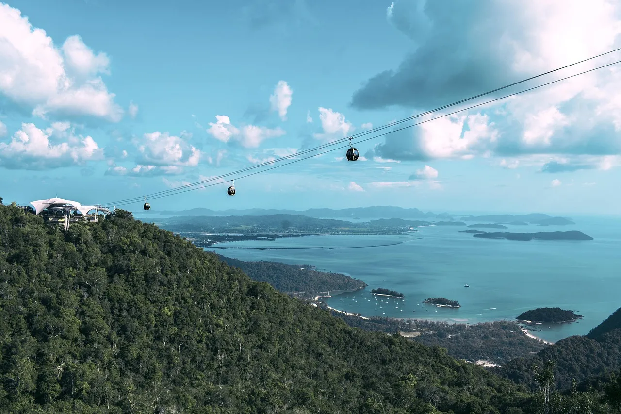 The Langkawi cable car rising over a forested hill, with green islands in a turquoise sea below