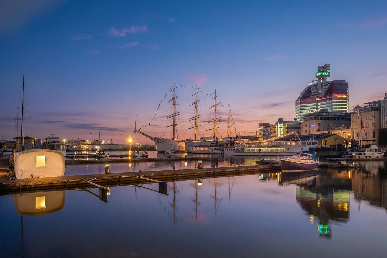 The tall ship Barken Viking moored in Gothenburg's Lilla Bommen harbour at dusk, with the red and white Lipstick building behind