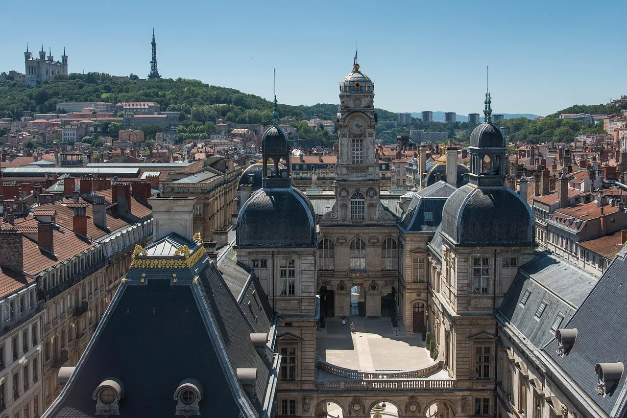 Lyon's Hôtel de Ville and old rooftops, with the white Basilica of Notre-Dame de Fourvière on the green hill behind
