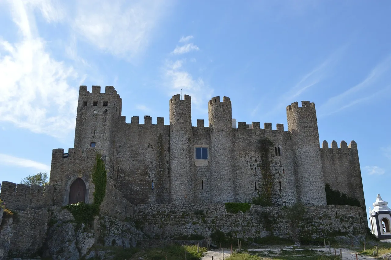 The walls and towers of Óbidos castle under a blue sky
