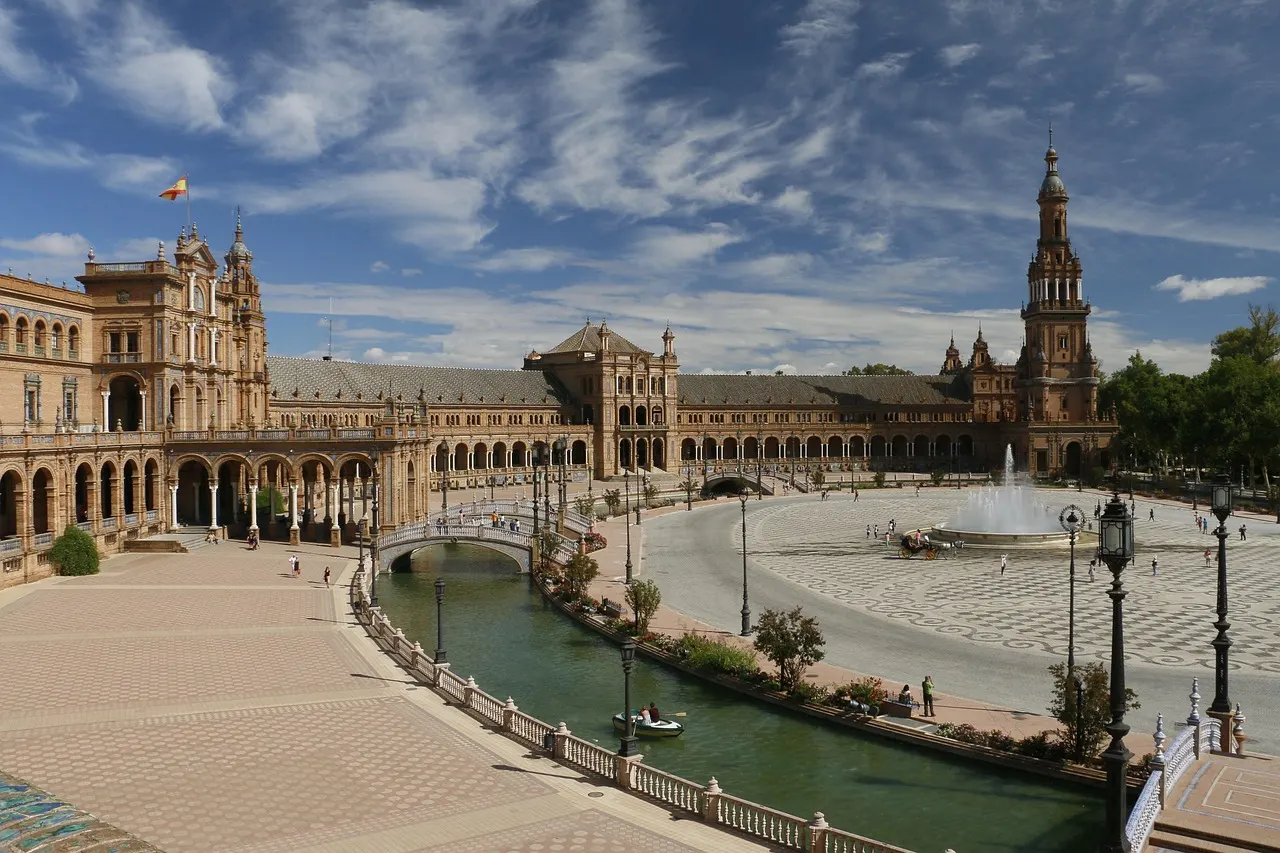The curved, tiled buildings and tower of Plaza de España in Seville, with a canal and bridges in front