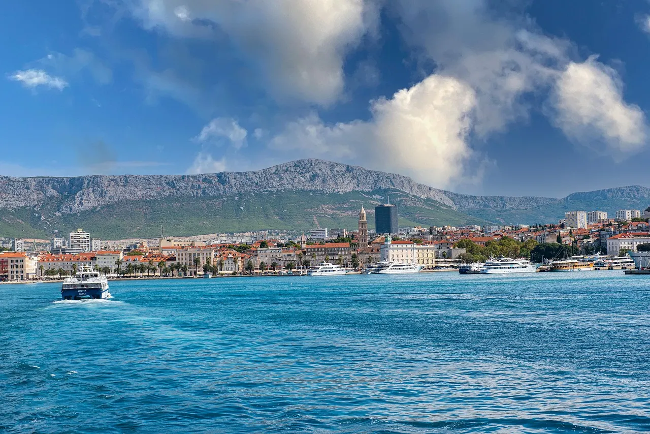 Split's seafront with boats in the harbour and the old town buildings, with mountains behind