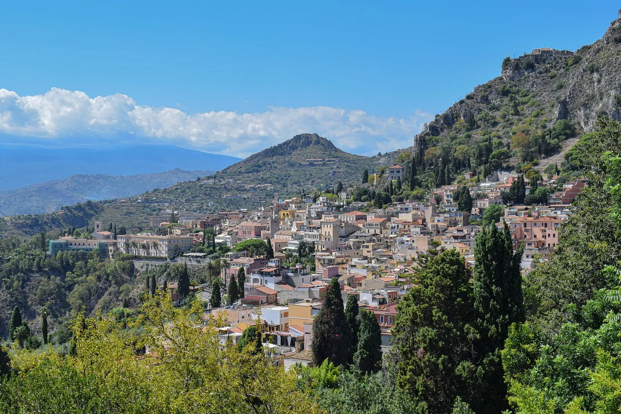 Taormina's houses spread across a green hillside above the sea