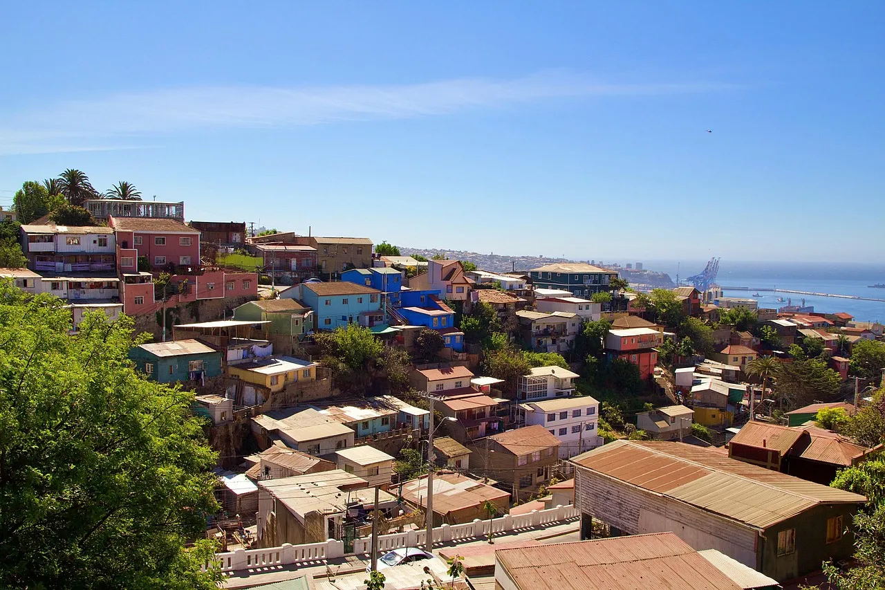 Brightly painted houses climbing a hillside in Valparaíso, Chile, with the port and Pacific Ocean behind