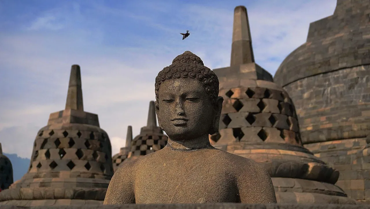 A stone Buddha among the bell-shaped stupas of Borobudur, near Yogyakarta